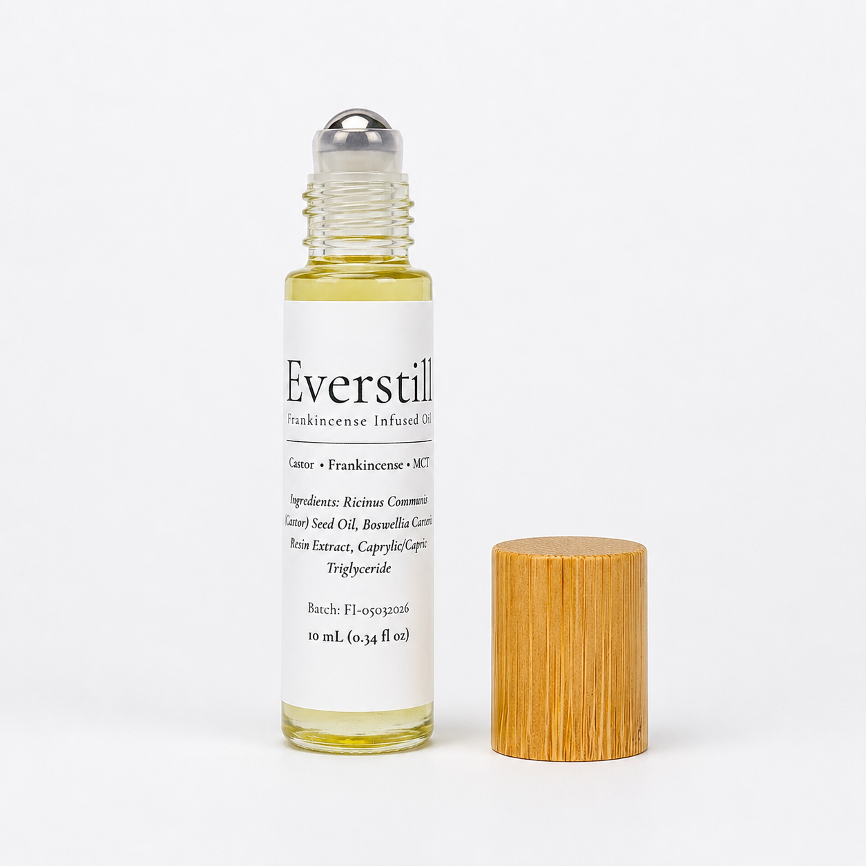Everstill Frankincense resin-infused castor oil roll-on with stainless steel roller ball and bamboo cap beside bottle